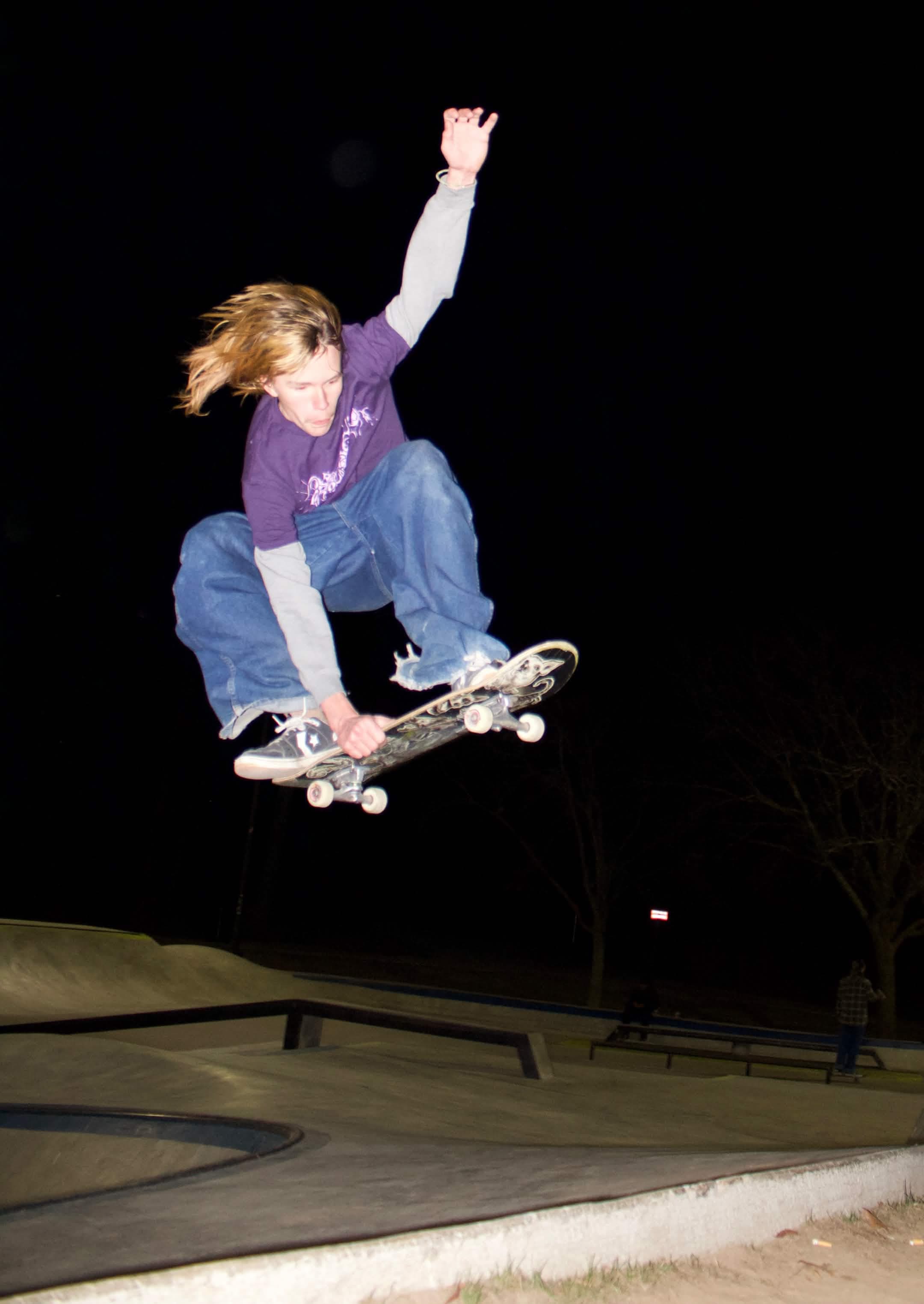 Skateboarder performing a night trick under dramatic lighting